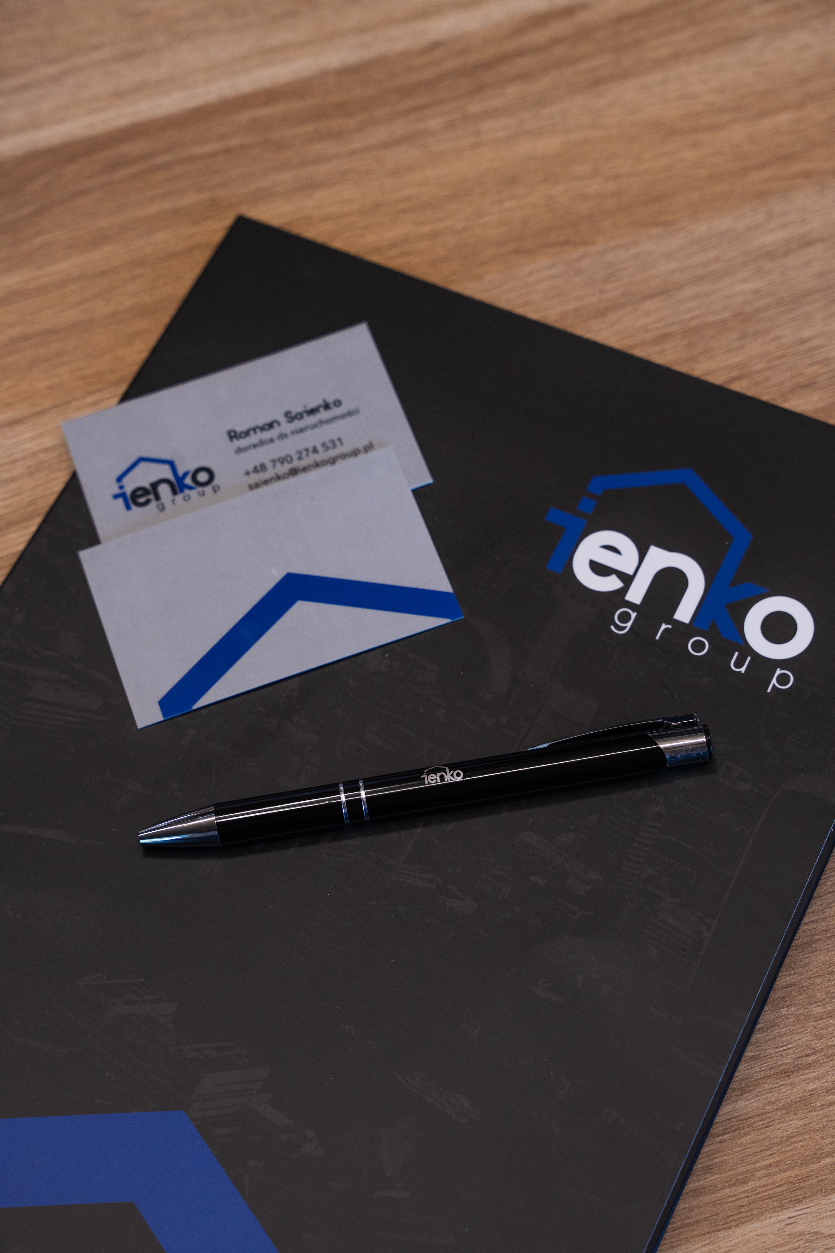 Branded folder i wizytówka ienko group na drewnianym stole